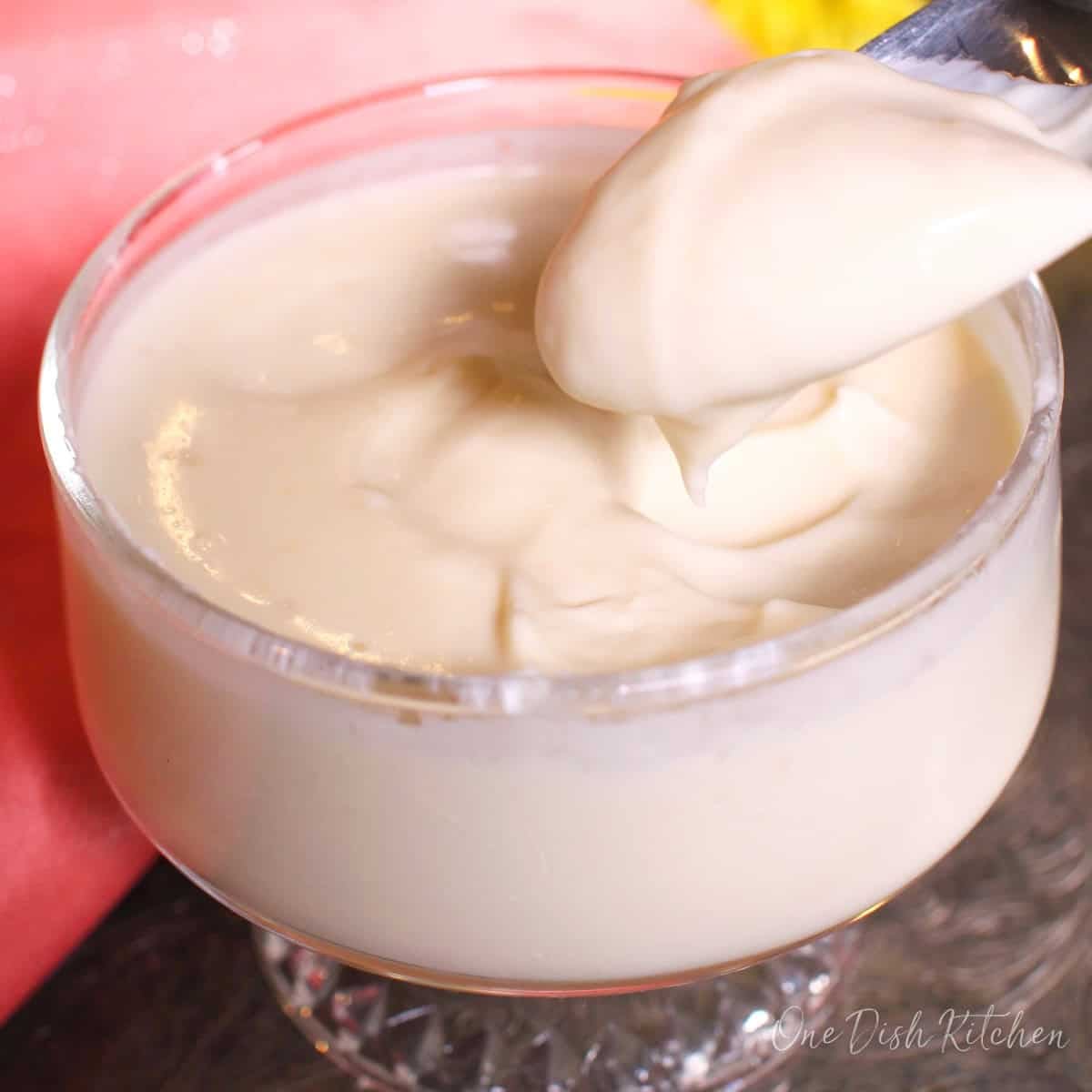 a grapefruit posset in a dessert dish with a spoon on the side.