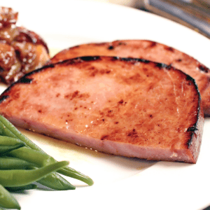 ham steak on plate with green beans.