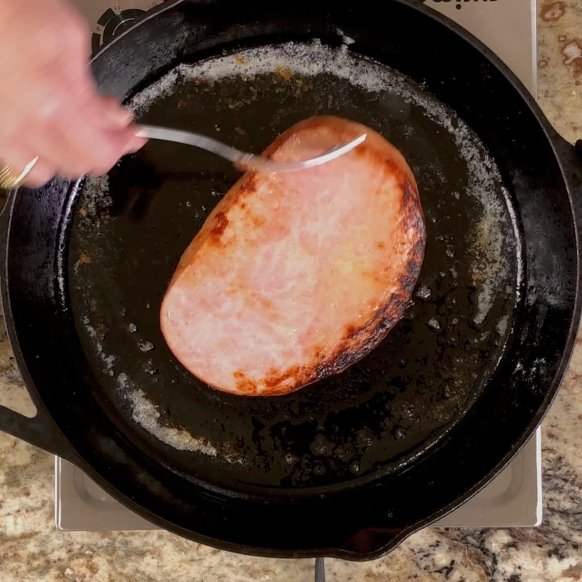 a ham steak cooked on one side and now cooking on the other.