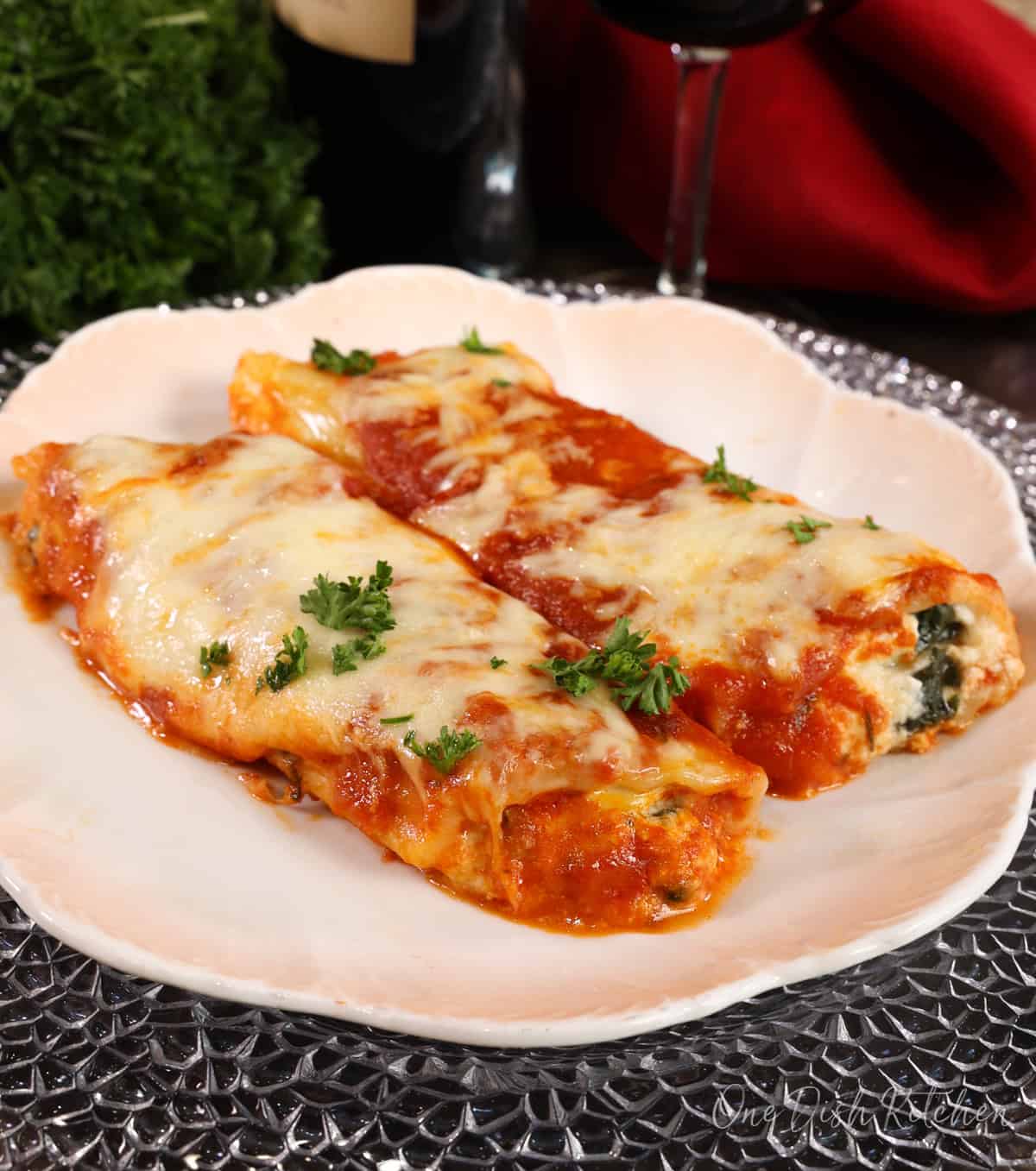 a small batch of spinach and cheese manicotti on a white plate.