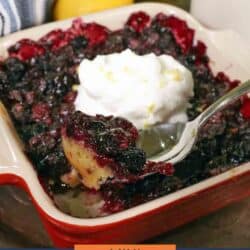 a small blueberry pie in a red baking dish topped with whipped cream.