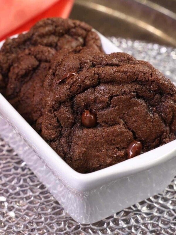 four double chocolate chip cookies in a mini white loaf pan next to an orange napkin