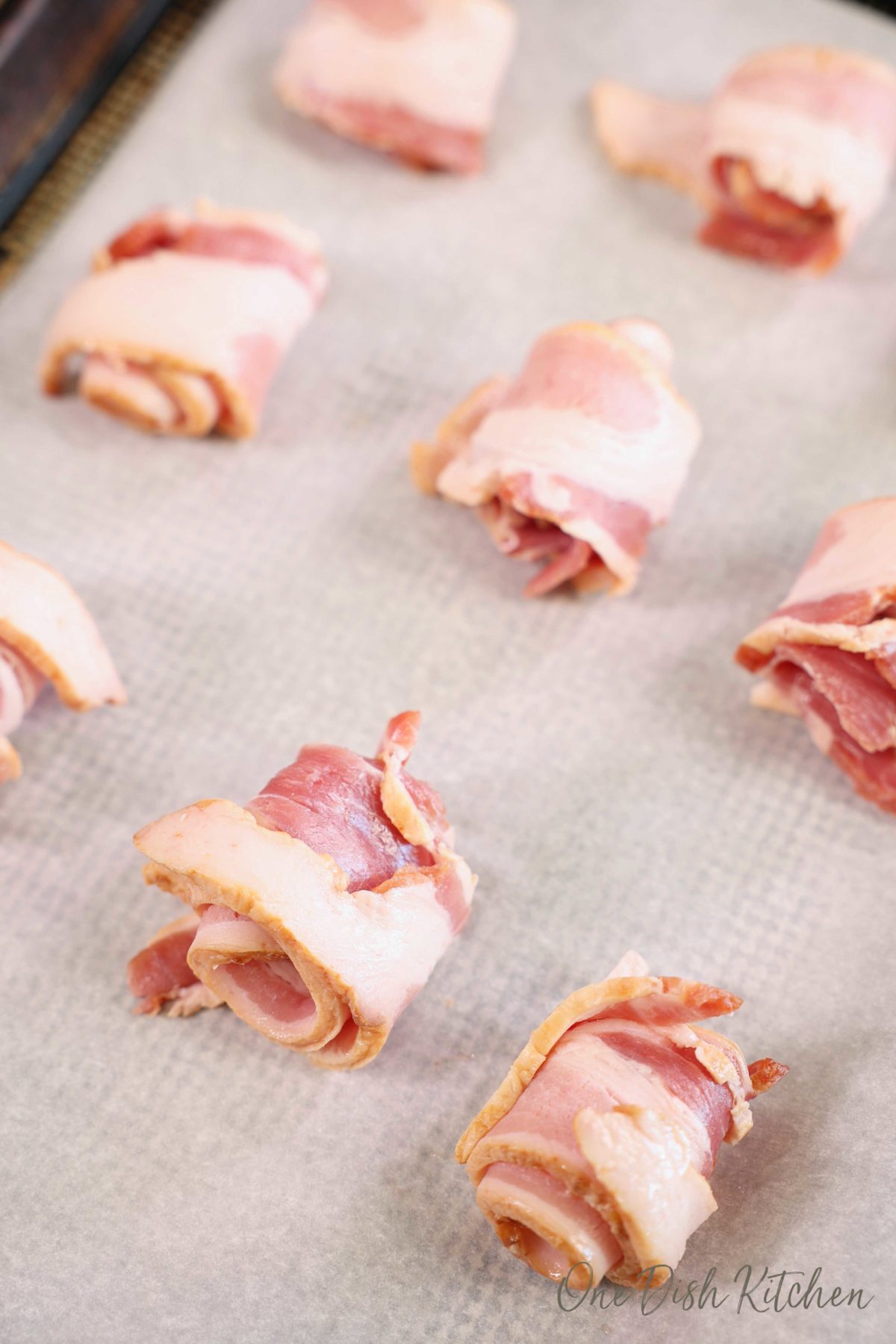 bacon strips rolled into spirals on a baking sheet