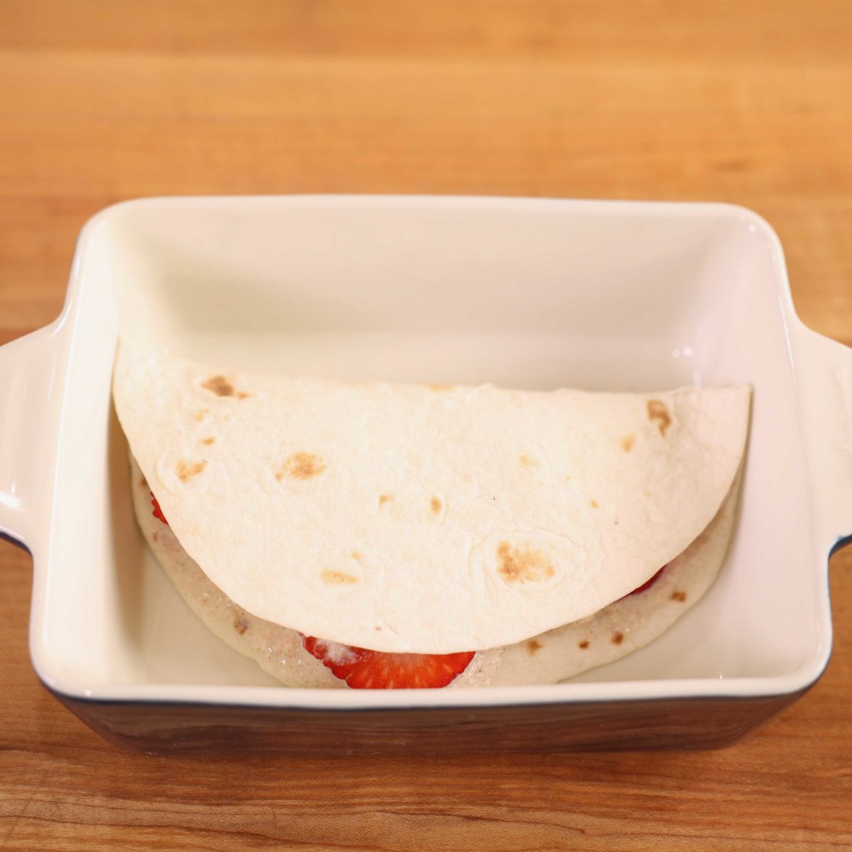 a tortilla filled with fruit folded over in a baking dish.