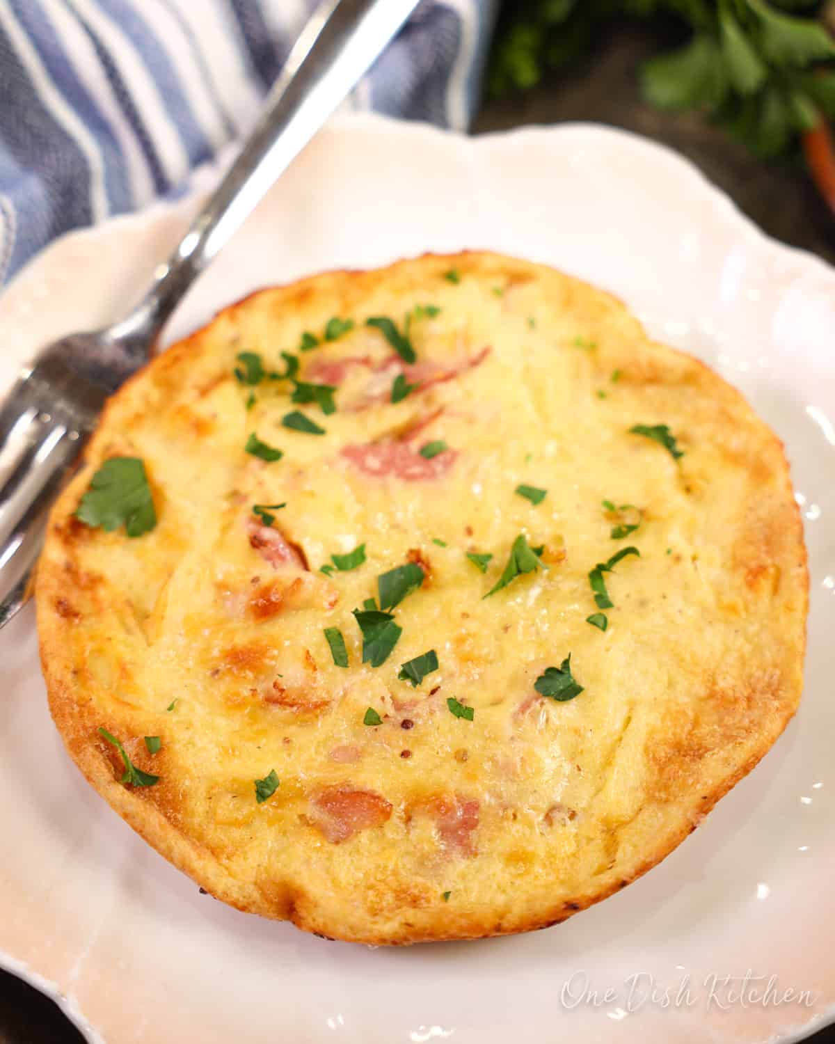 a small ham and cheese dutch baby next to a blue napkin.