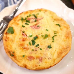 a small ham and cheese dutch baby next to a blue napkin.
