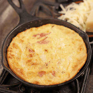 a baked dutch baby fresh out of the oven and puffy in a cast iron skillet.