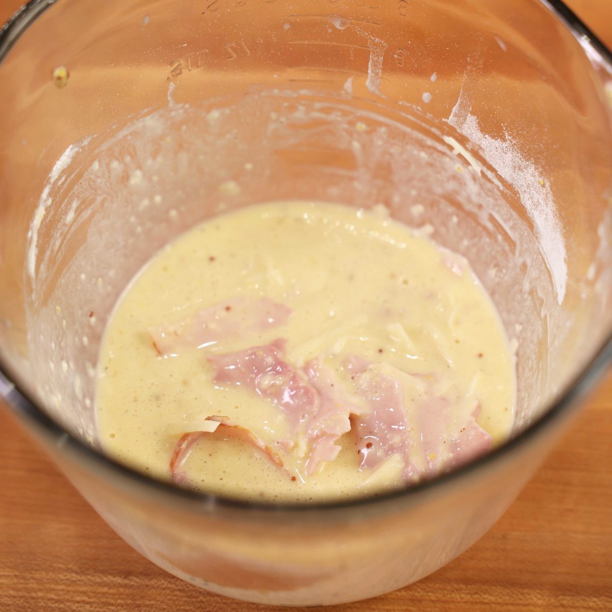 egg, milk, flour, spices, and mustard in a clear mixing bowl.
