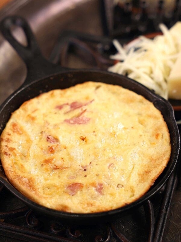 a baked dutch baby fresh out of the oven and puffy in a cast iron skillet