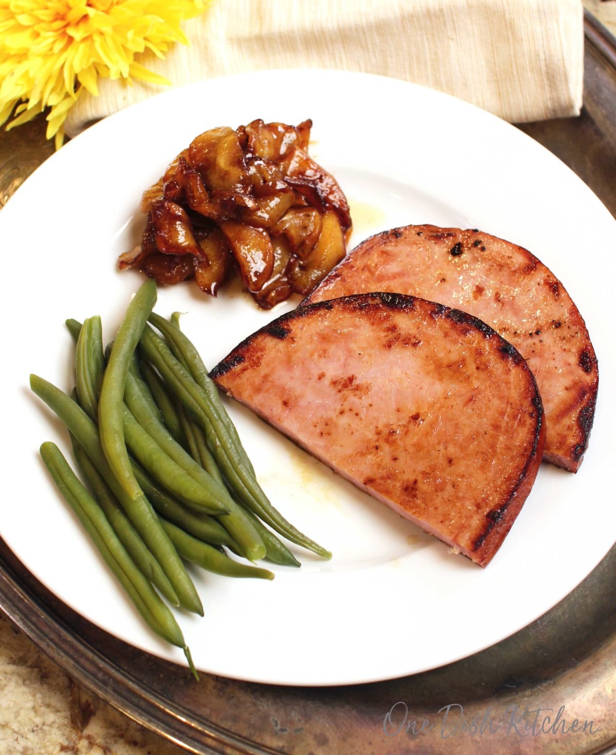 ham steak on plate with green beans.