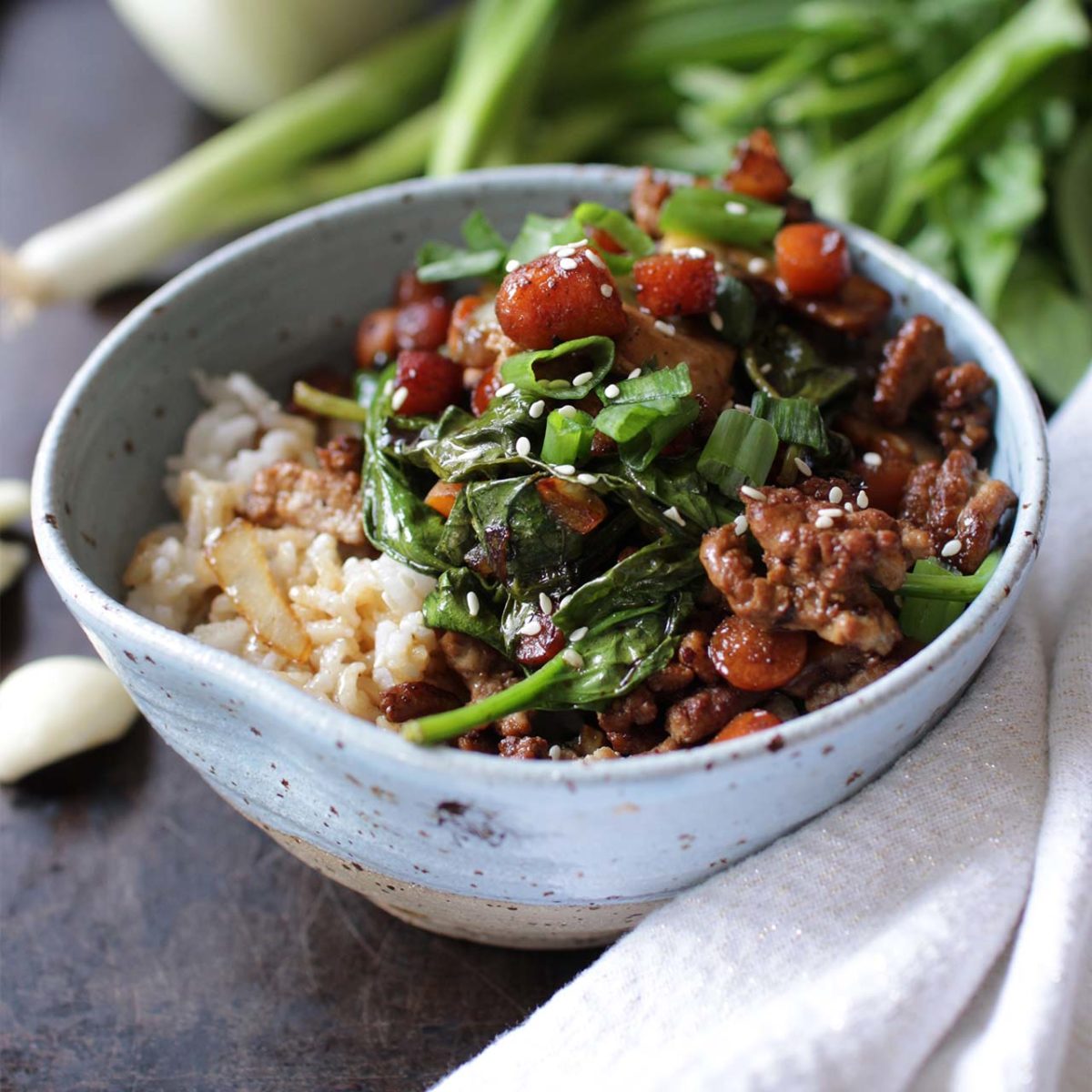 a blue bowl filled with ground pork, spinach and rice.