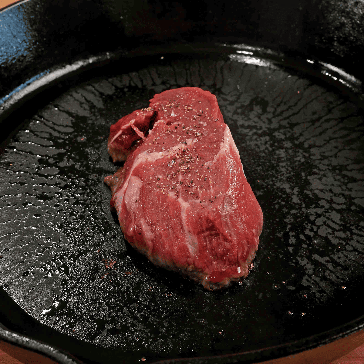 a raw beef tenderloin steak in a cast iron skillet.
