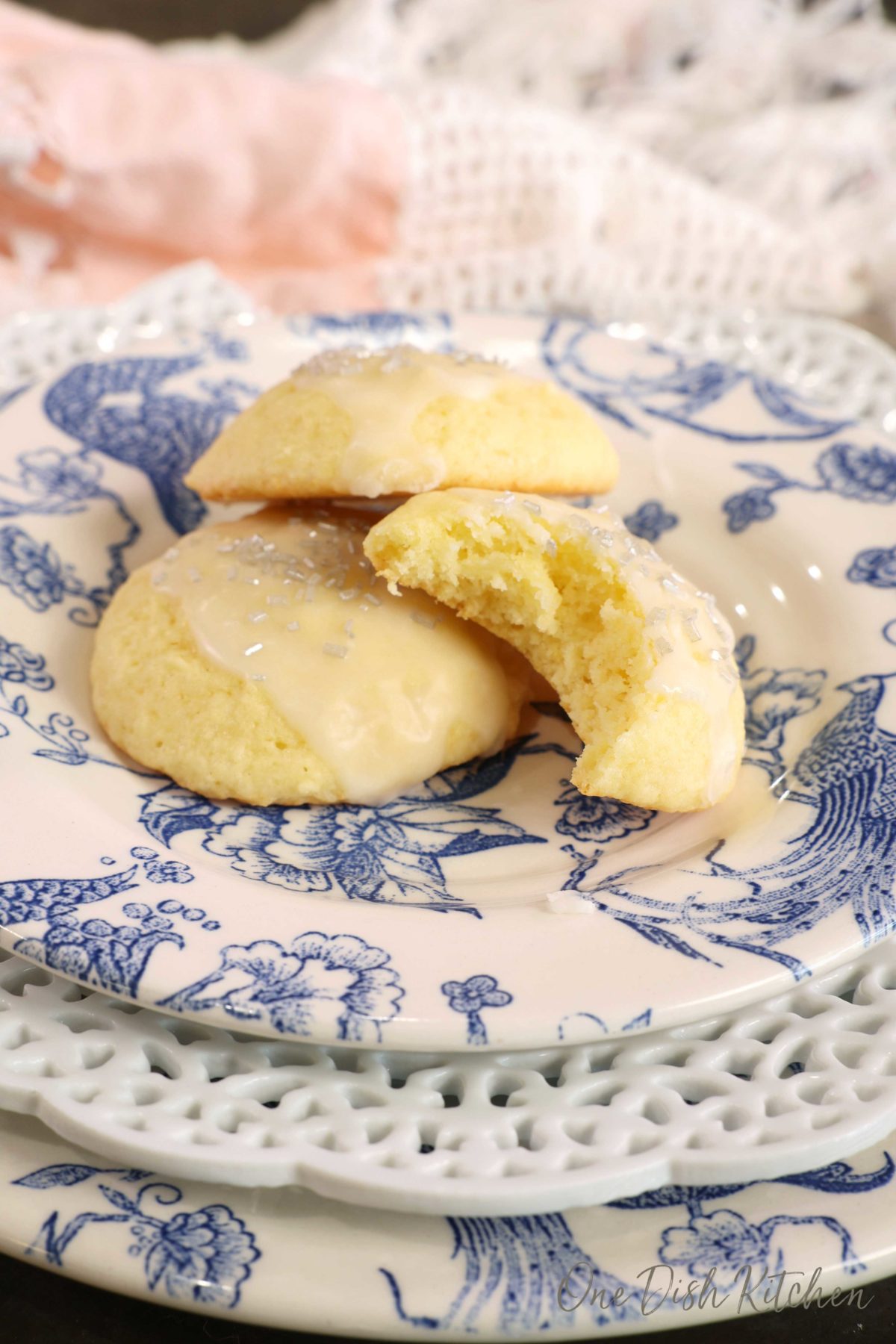 two ricotta cookies on a blue and white plate with one cookie having a bite taken out of it.