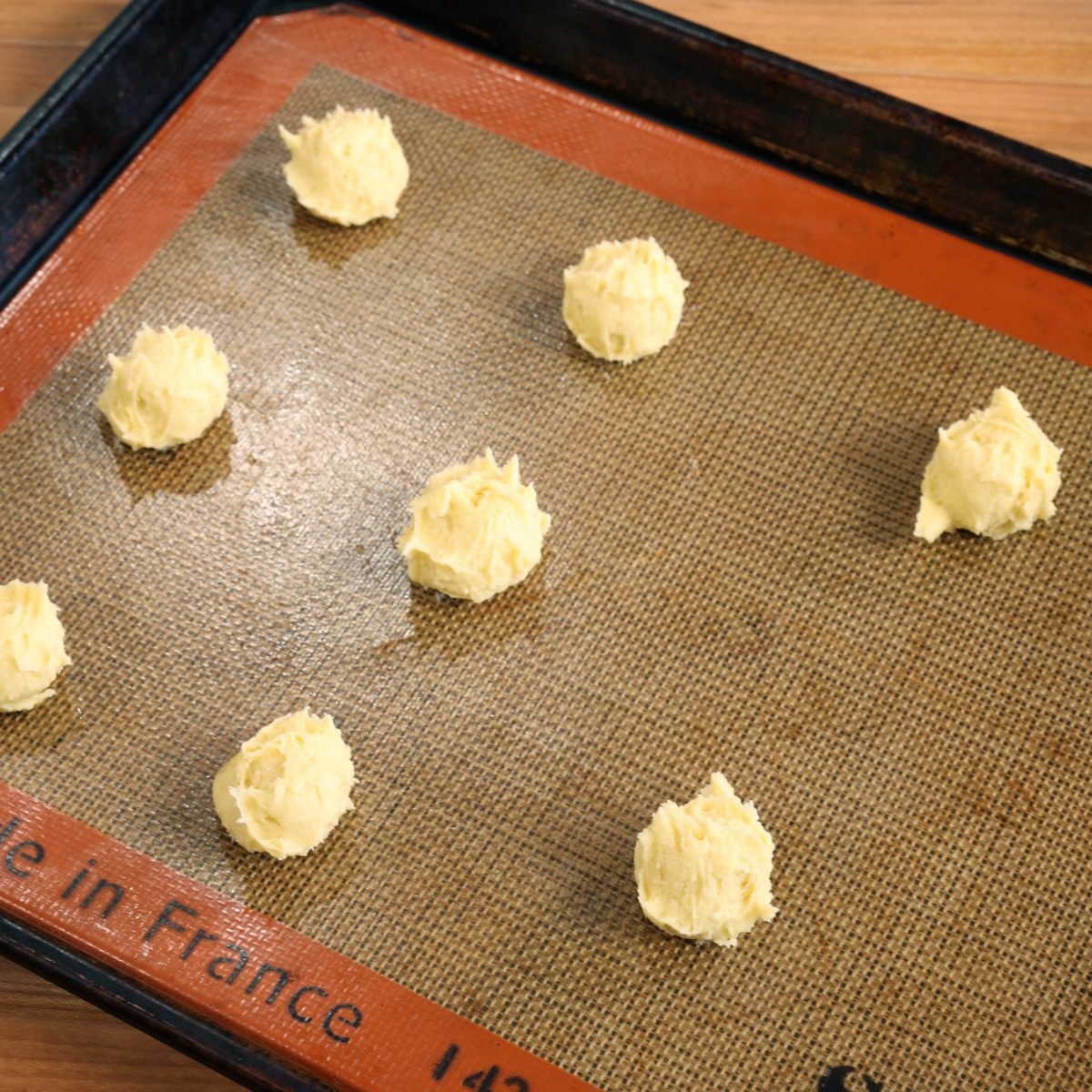 8 balls of cookie dough on a baking sheet.