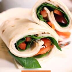 a turkey wrap with spinach and peppers on a white plate.