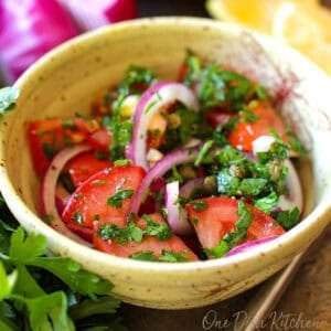 a fresh tomato salad with a lemon dressing in a yellow bowl.