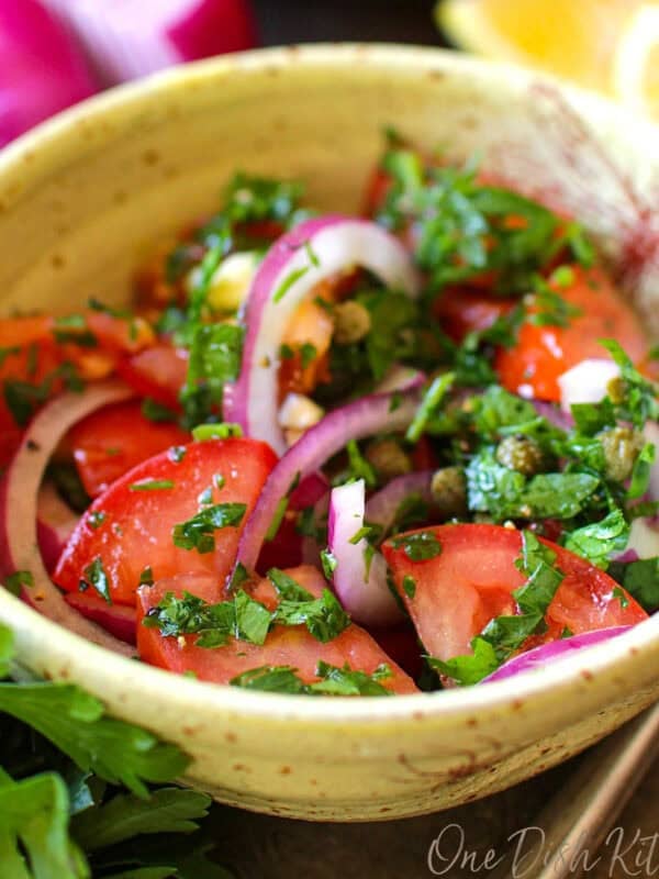 a fresh tomato salad with a lemon dressing in a yellow bowl.