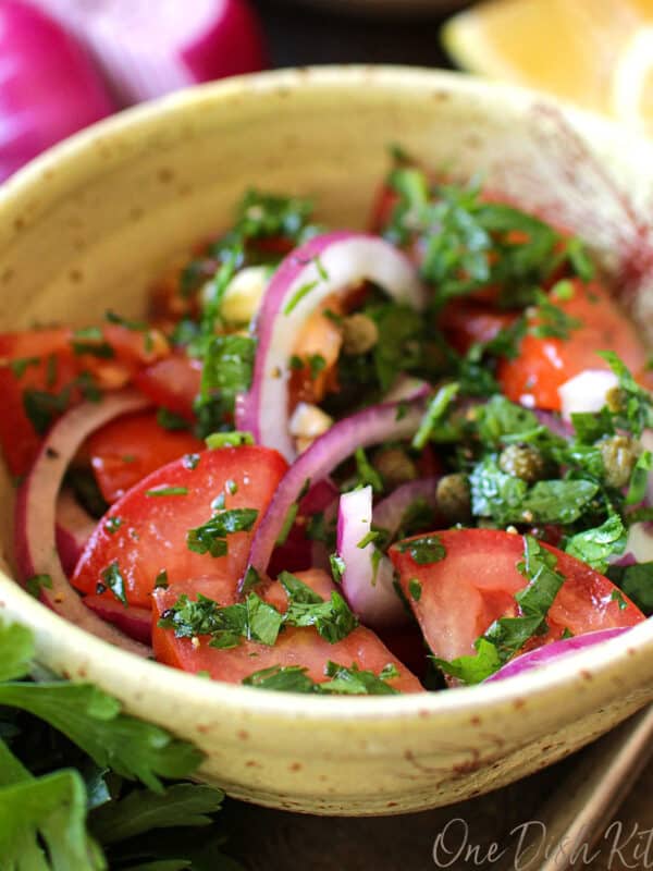 a salad filled with fresh tomatoes and onions in a yellow bowl.