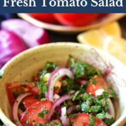 a tomato salad in a yellow bowl topped with parsley and red onions.