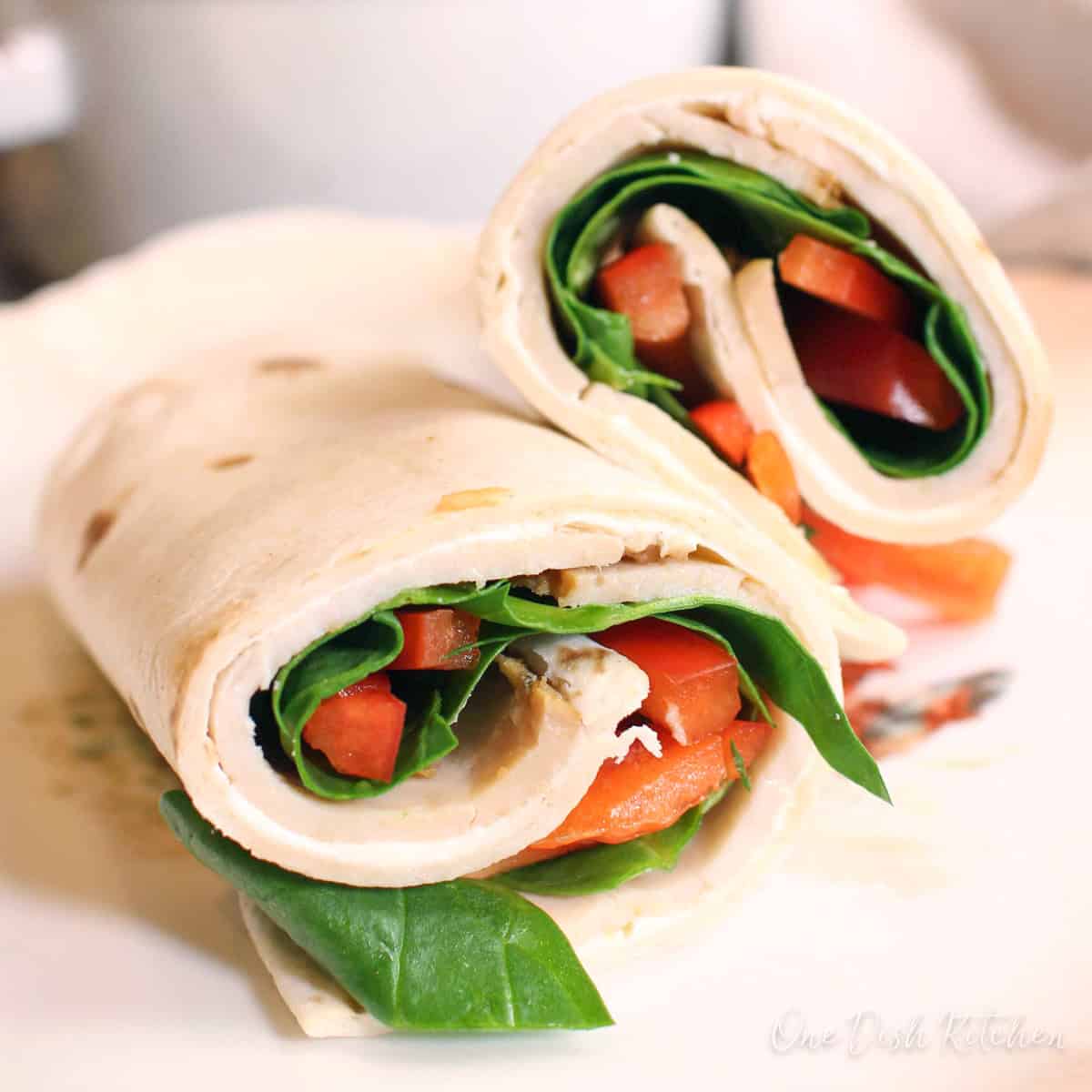 a turkey wrap sliced in half on a plate.