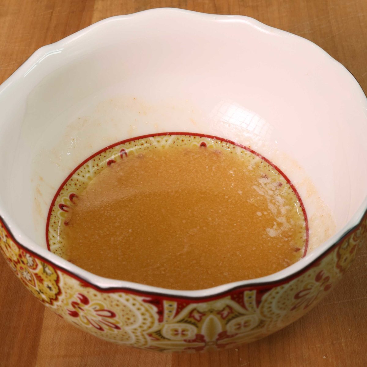 homemade buffalo sauce in a small red and white bowl on a wooden table