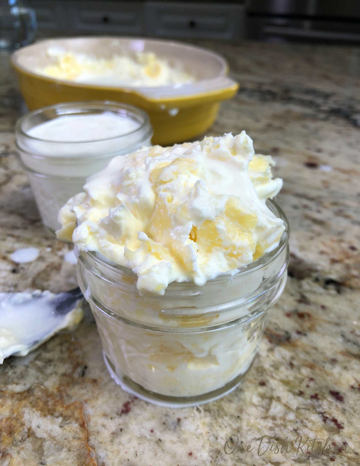 an overflowing jar of homemade clotted cream with the liquid in a jar in the background