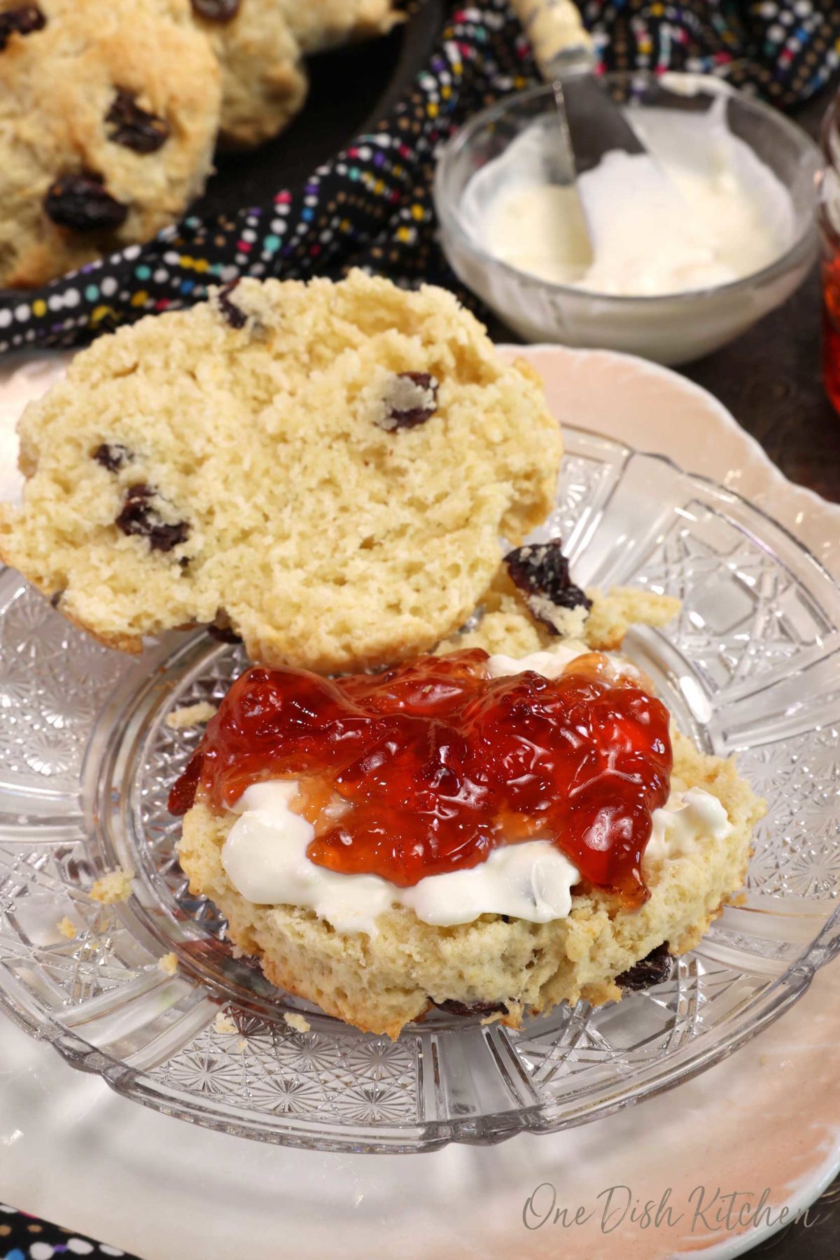 a scone sliced in half with one side topped with clotted cream and jam