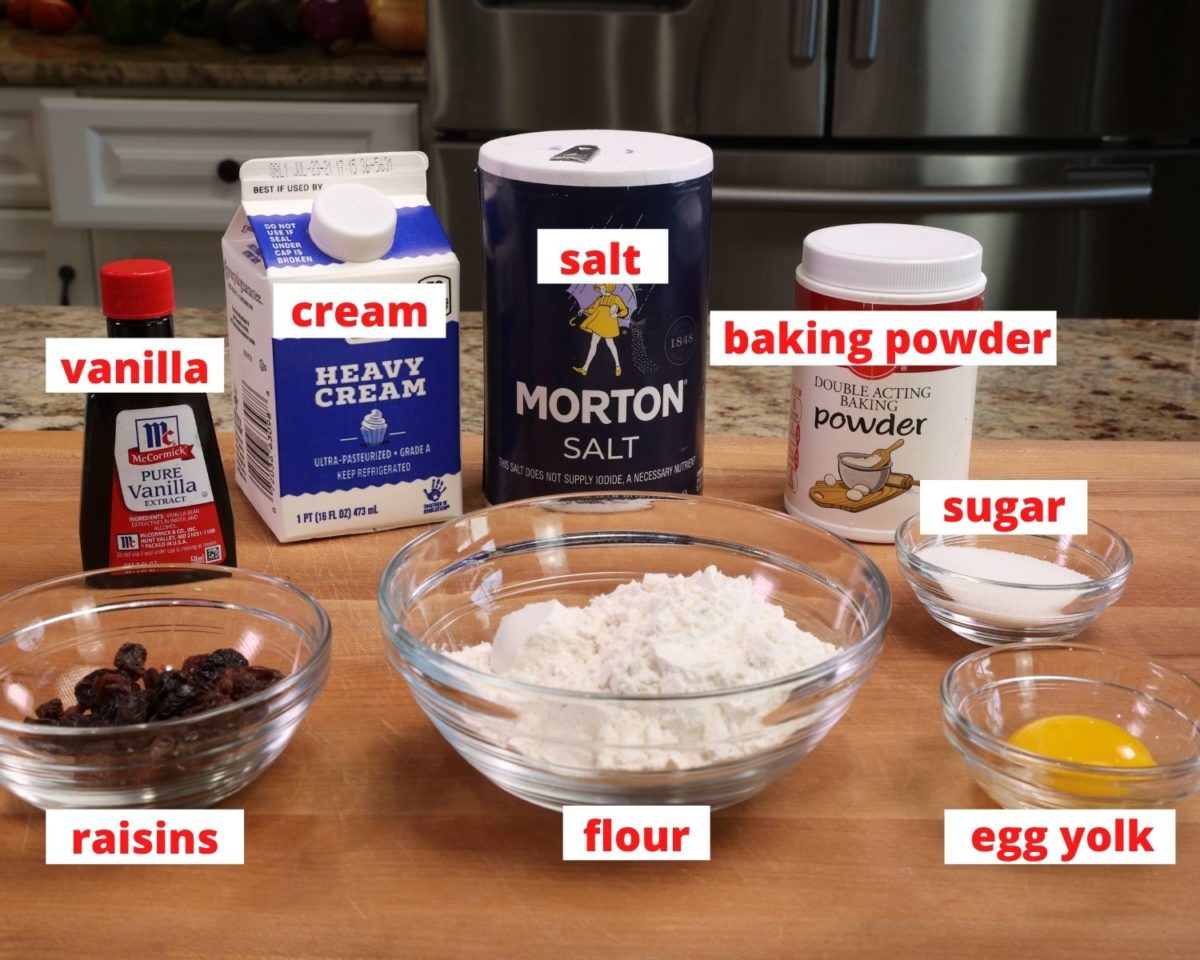 flour, cream, sugar, egg, baking powder and salt on a wooden cutting board.