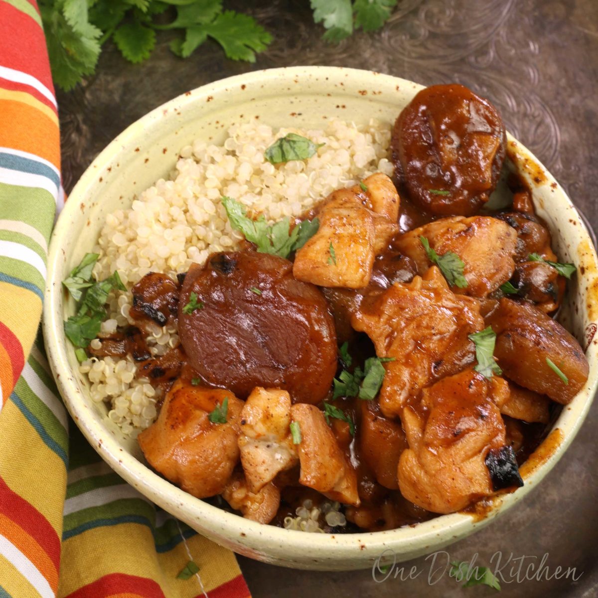 a bowl of eggplant and chicken tagine served over quinoa on a silver tray.