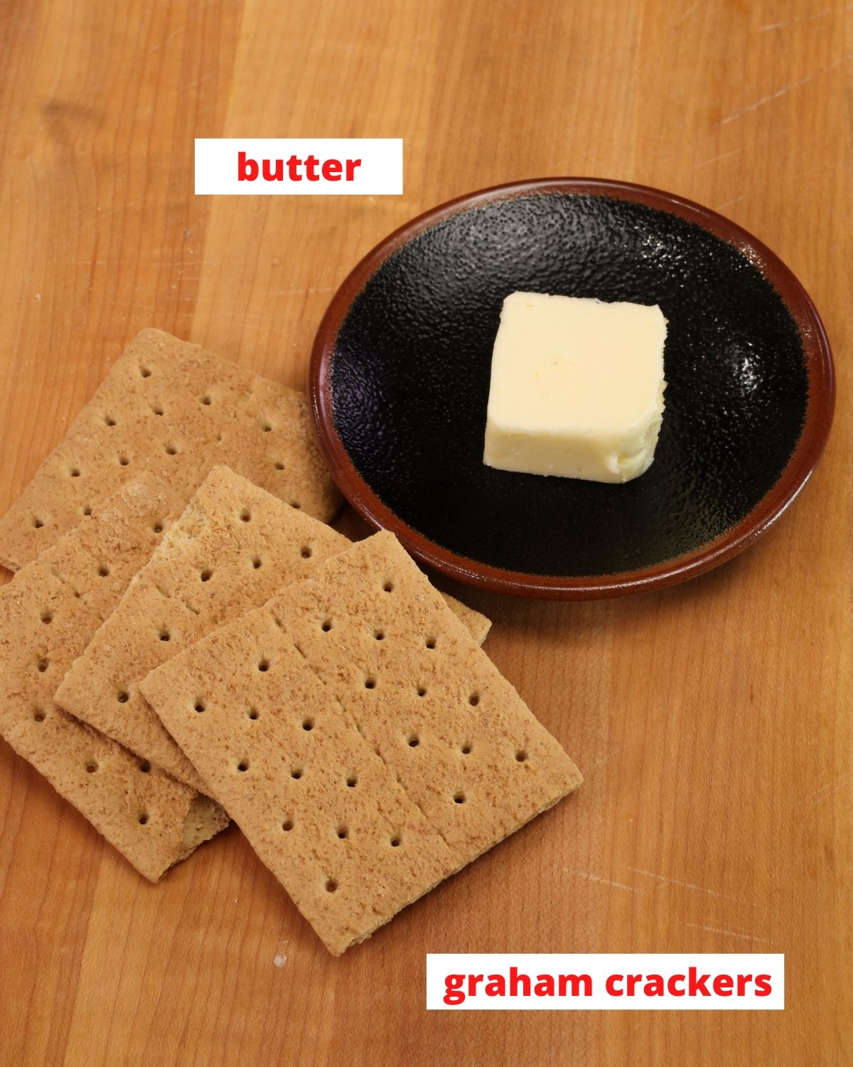 graham crackers and a tablespoon of butter on a wooden cutting board.