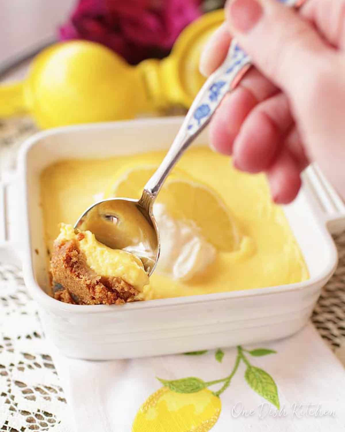 a spoonful of lemon pie next to the larger pie on a napkin with a lemon on it.
