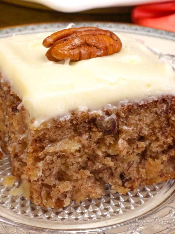 a slice of hummingbird cake made with one banana, pineapple and pecans under a cream cheese frosting.