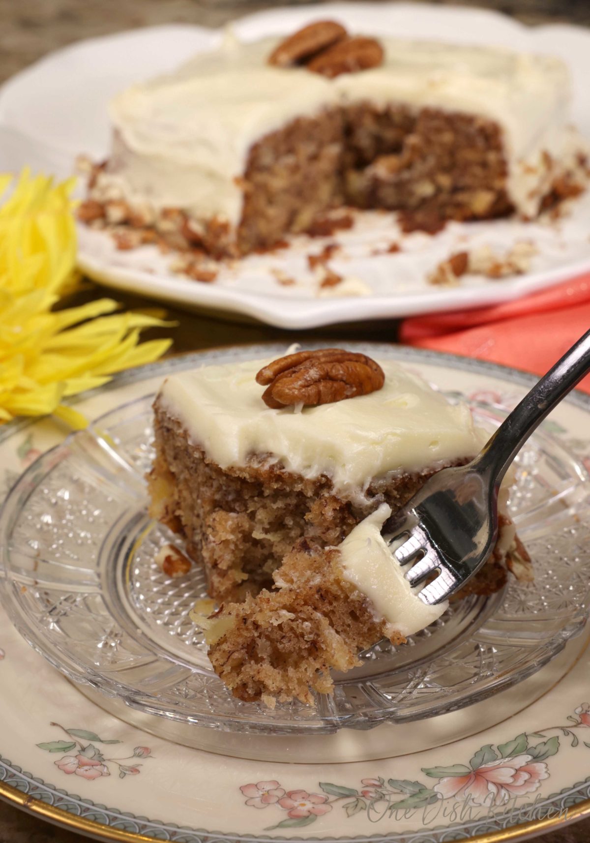a fork with a piece of hummingbird cake on the tip next to a larger plate with slices of cake.