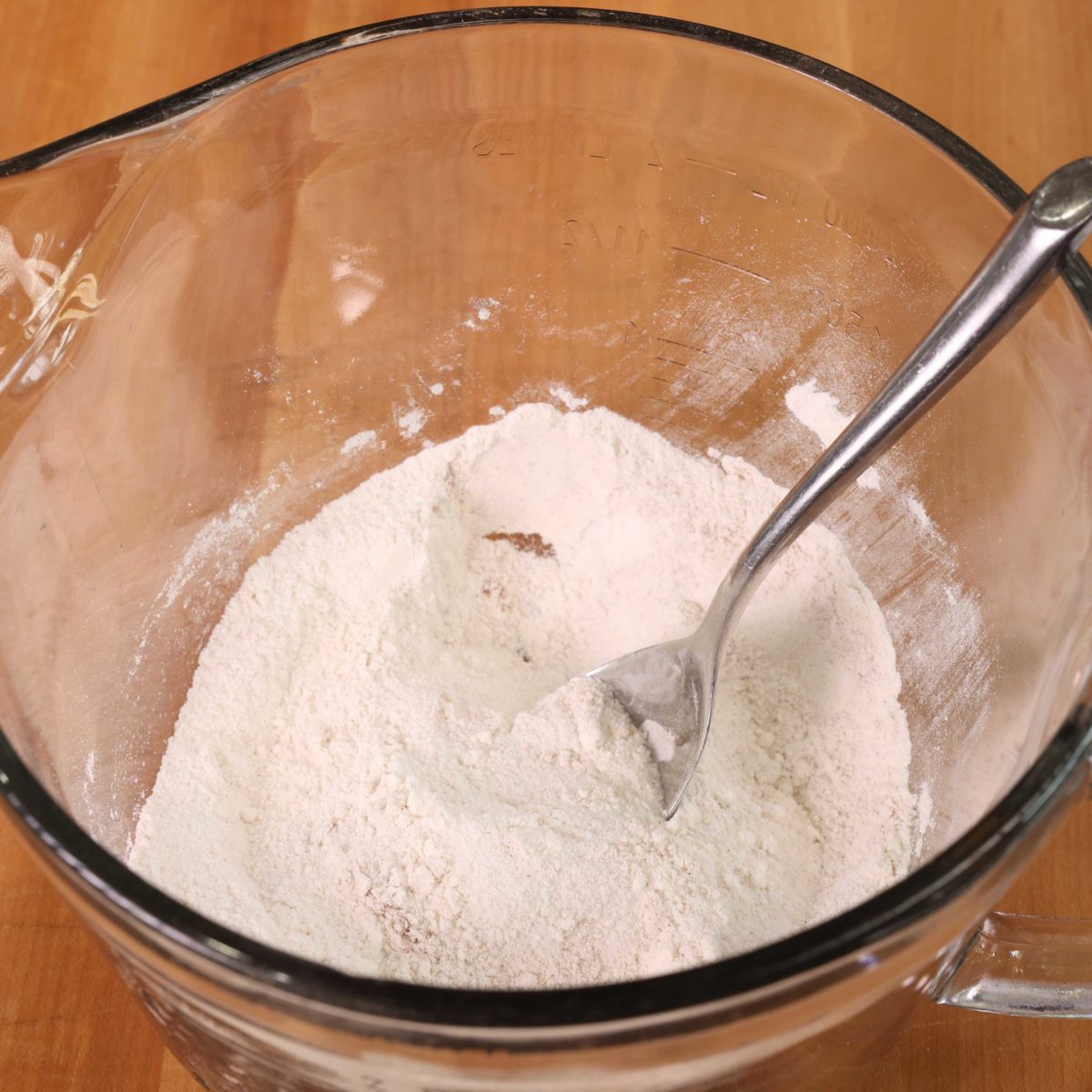a clear mixing bowl filled with flour, salt, and baking soda.