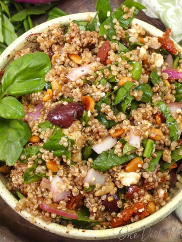 a small mediterranean quinoa salad in a yellow bowl with olives, feta and tomatoes.