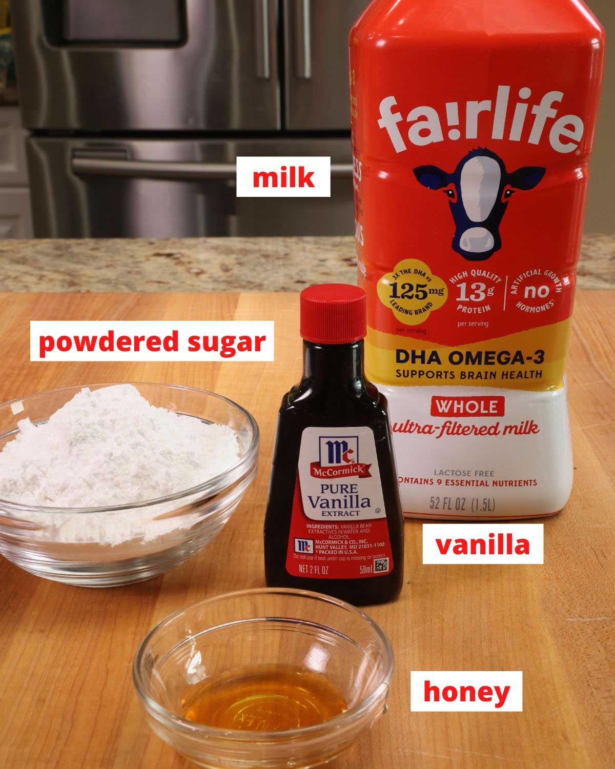 Ingredients for peach scone glaze: powdered sugar, milk, vanilla and honey on a wooden cutting board.