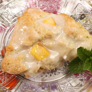 a peach scone with a vanilla glaze on a flowered plate.