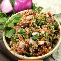 a quinoa salad with olives, tomatoes, and onions in a yellow bowl.
