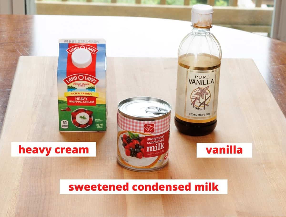 heavy cream, sweetened condensed milk, and vanilla extract on a wooden cutting board in a kitchen