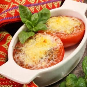 one broiled tomato sliced in half topped with cheese in a dish.