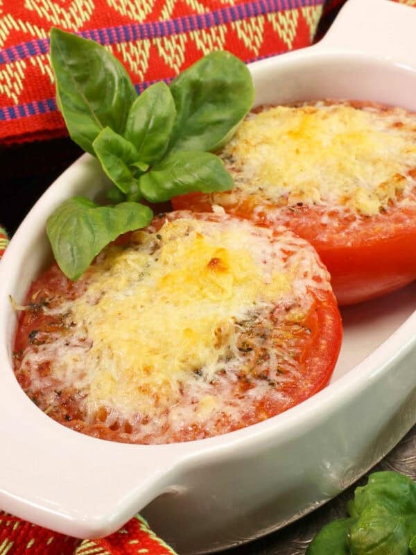 one broiled tomato sliced in half topped with cheese in a dish.