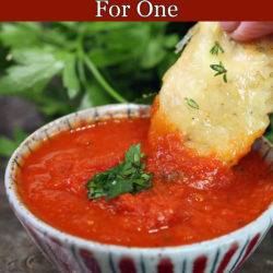 marinara sauce in a small bowl with a chicken tender held by a hand and dipped into the sauce