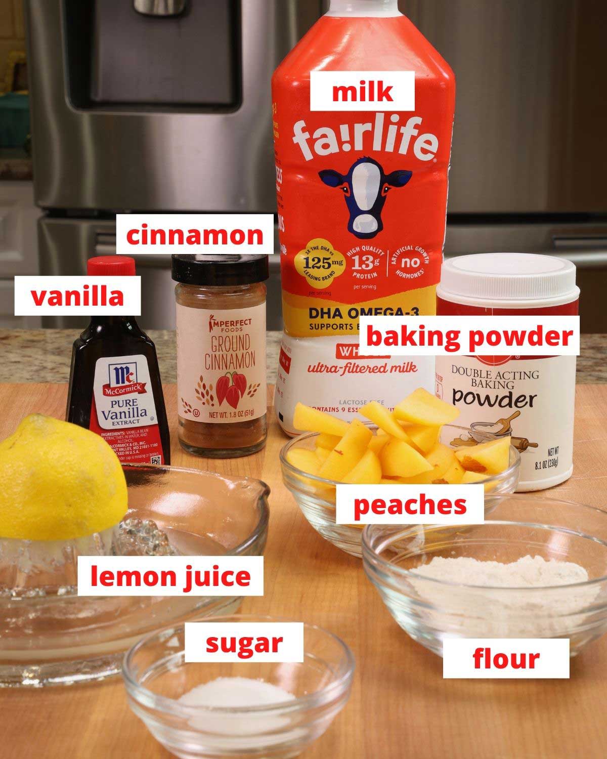 flour, peaches, lemon juice, vanilla, baking powder and sugar on a wooden cutting board.