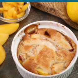a biscuit topped peach cobbler in a small white ramekin next to a bowl of chopped peaches