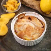 a single serve peach cobbler on a silver tray surrounded by slices of a fresh peach.