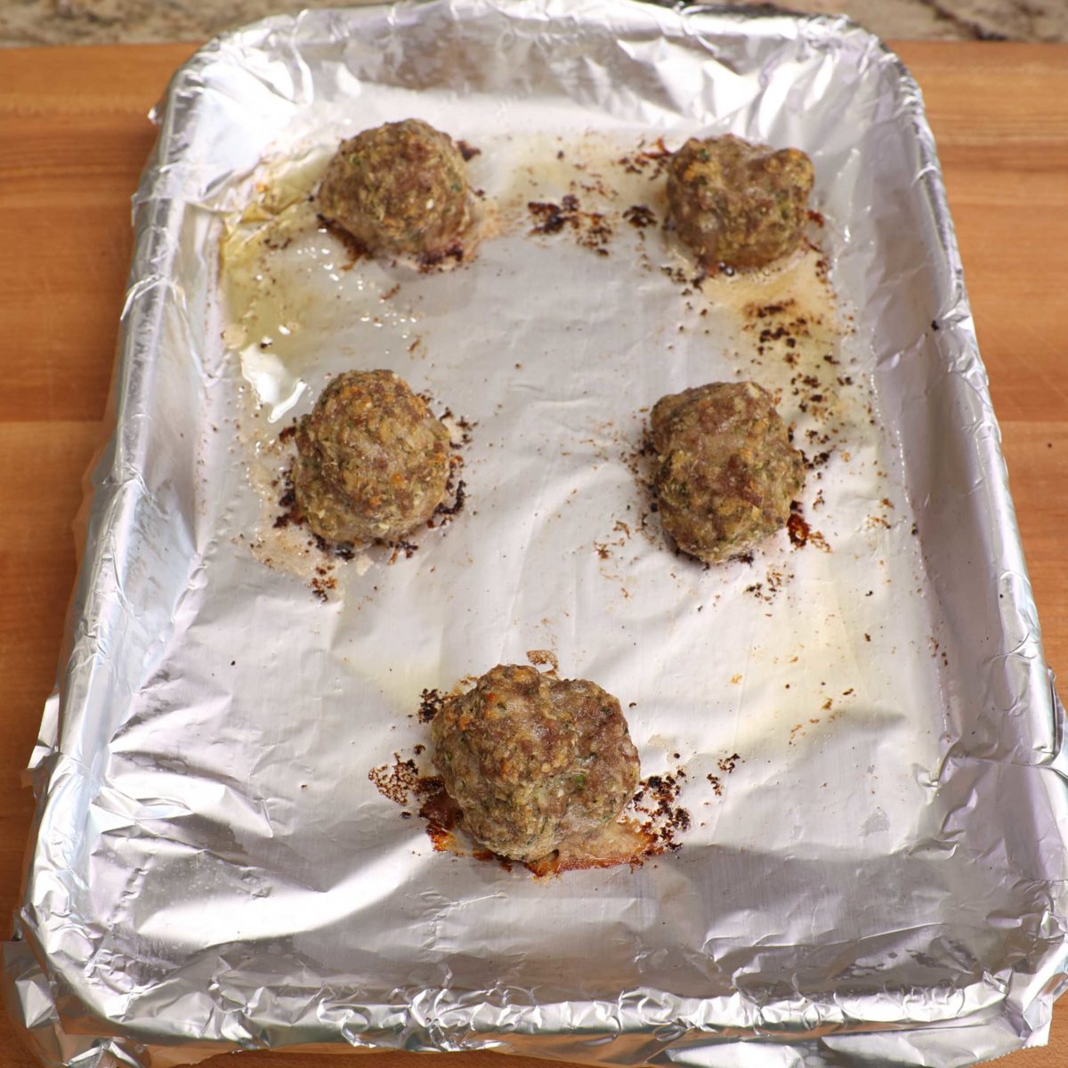 cooked meatballs on a baking sheet.