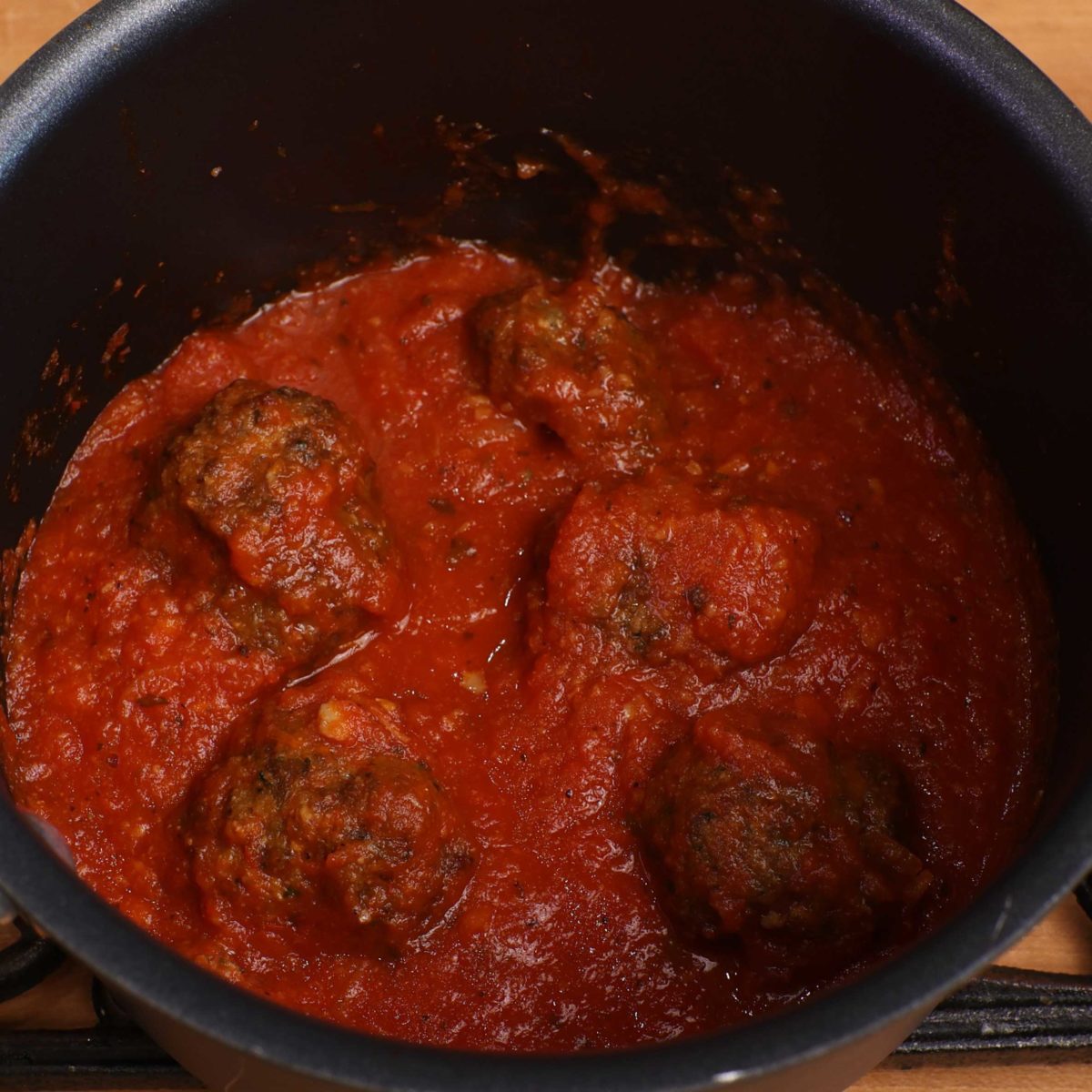 meatballs simmering in a pot of spaghetti sauce.