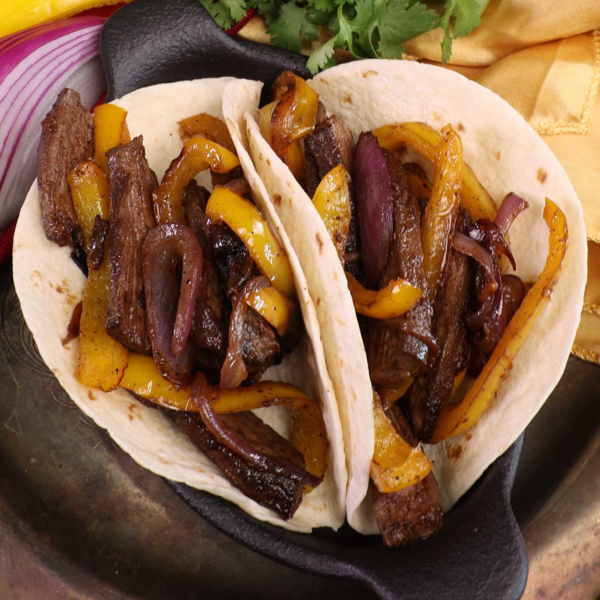 two flour tortillas filled with steak and vegetables.