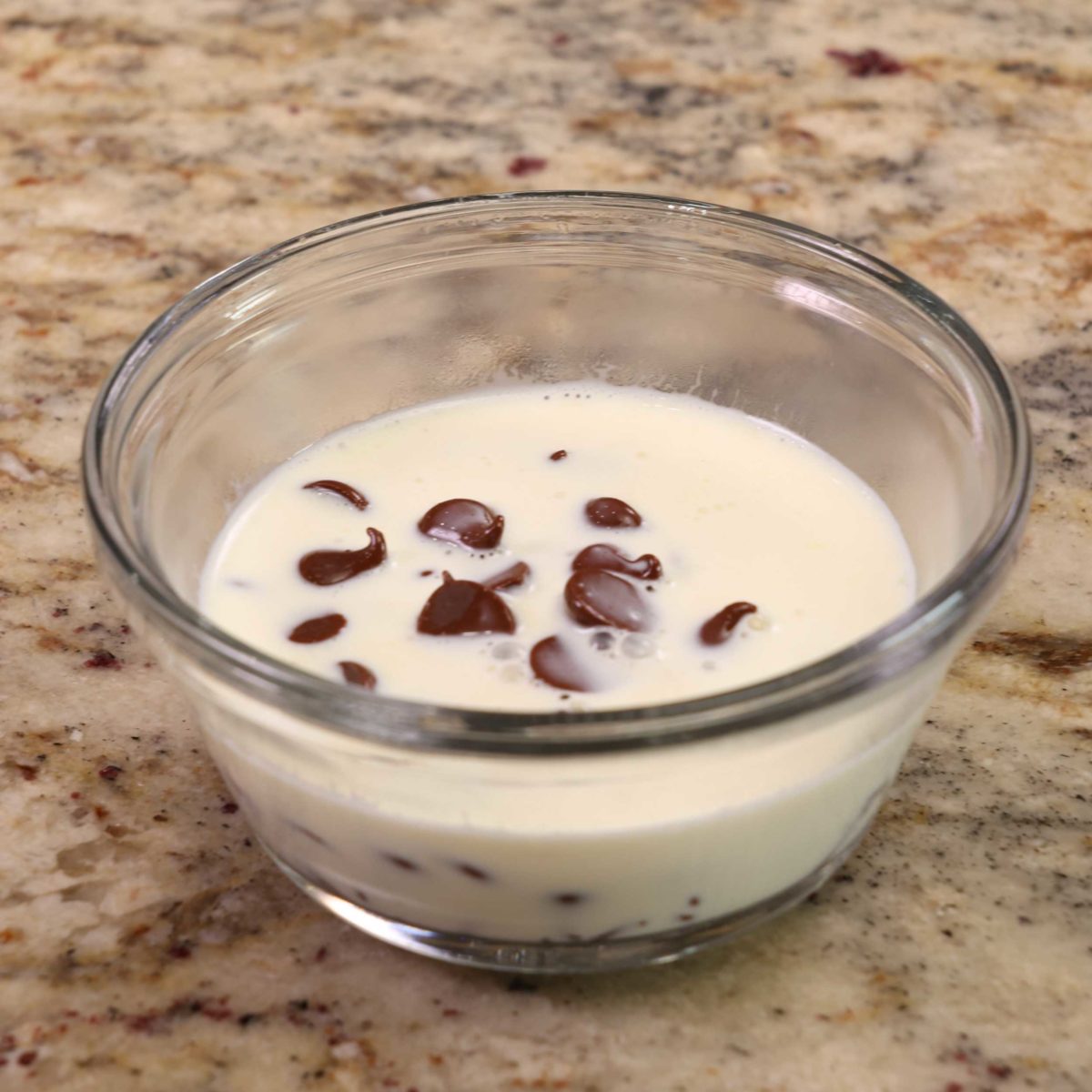 chocolate chips and warmed cream in a small clear glass bowl