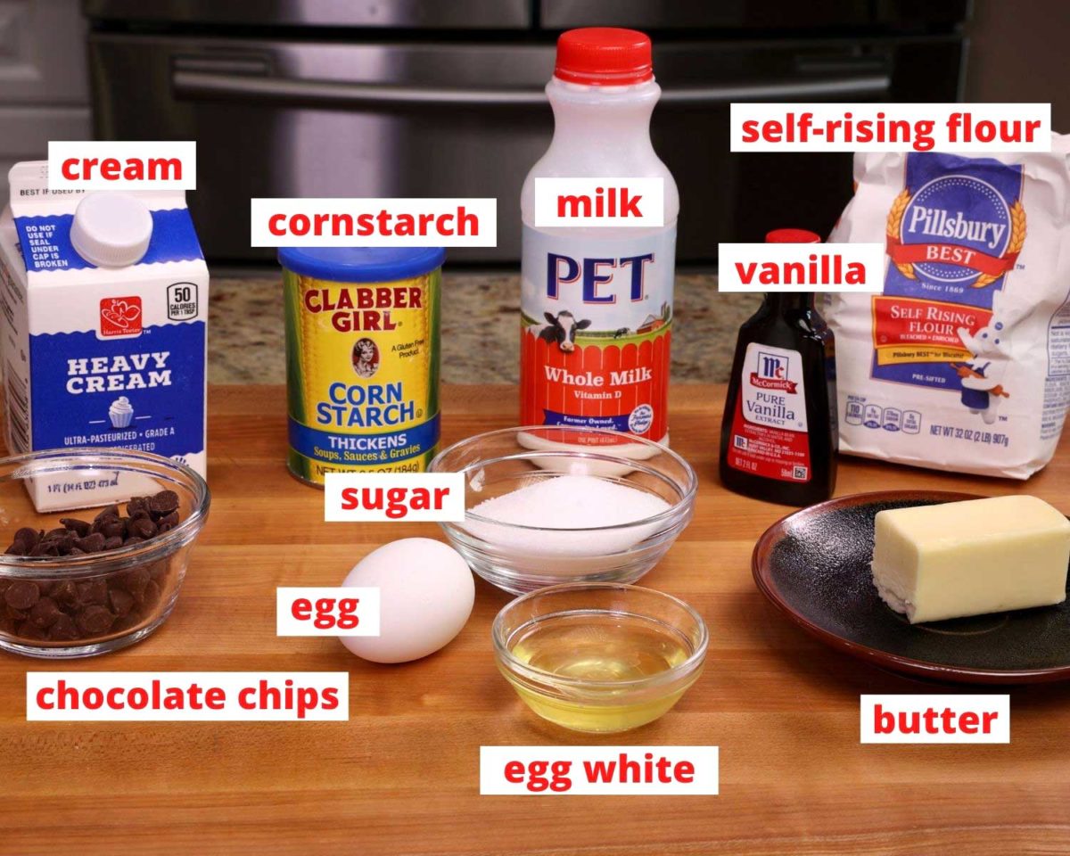cream, chocolate, cornstarch eggs, sugar, milk, flour, vanilla and butter on a wooden cutting board